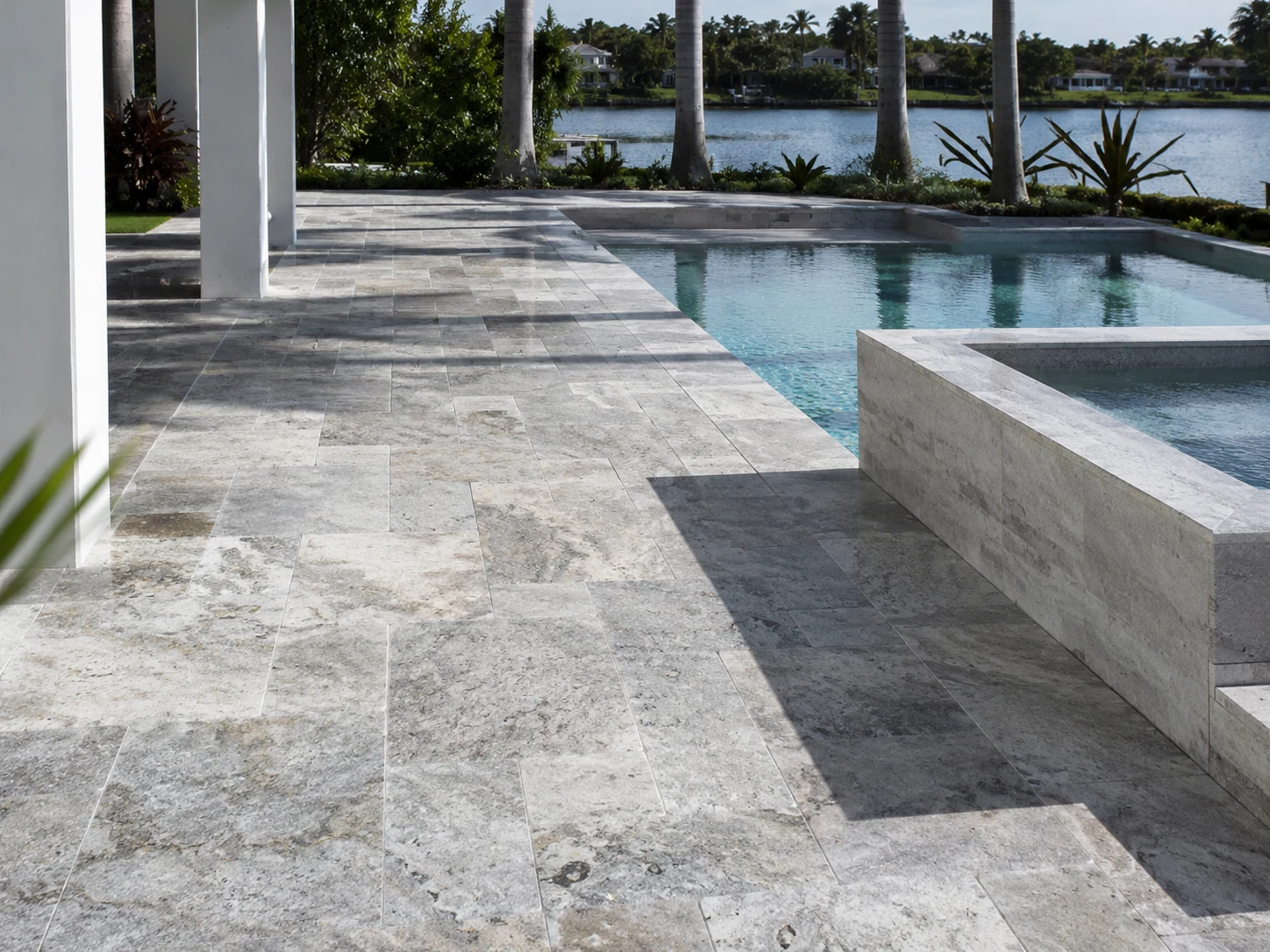 Cool-tone travertine pool deck with gray and silver natural stone notes